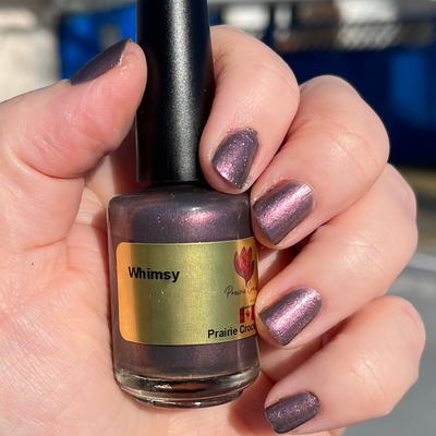 Whimsey by Prairie Crocus Polish, smokey mauve shimmer with pink-to-purple shift, bottle held in a light skin tone hand