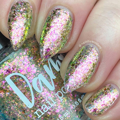 Ayla the Scoliosis Dolphin by Dam Nail Polish, multichrome flakie with large pink, gold, and green-to-blue shifting flakes under direct flash, on a light skin tone hand