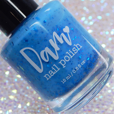 Blueberry Sanctuary by Dam Nail Polish, medium sky blue holographic shimmer flakie crelly with metallic blue glitter and blue-purple shifting shimmer, bottle standalone product shot