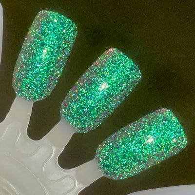 Permit to Hermit by Dam Nail Polish, neon green reflective glitter flash with teal shimmer and soft pink-purple flakie shift under direct flash, swatch stick