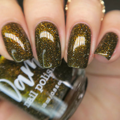 Champagne Sparkles by Dam Nail Polish, black jelly base with dense bronze-gold shimmer and gold reflective glitter sparks, on a light skin tone hand