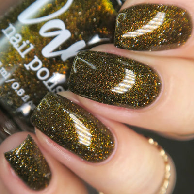 Champagne Sparkles by Dam Nail Polish, olive-black jelly with bronze shimmer and gold reflective micro-glitter in bright daylight, on a light skin tone hand