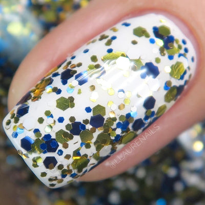 Kintsugi by Dam Nail Polish, black-blue glitter topper with gold, cobalt blue, and white mixed-size hex glitters over white creme base, on a light skin tone hand