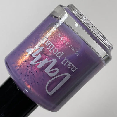 Winter Wisteria by Dam Nail Polish, medium lavender purple base with vivid pink-magenta to warm orange-gold multichrome shimmer, bottle standalone product shot