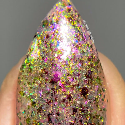 Ayla the Scoliosis Dolphin by Dam Nail Polish, macro close-up of gold, magenta-red, and blue-to-green shifting multichrome flakies over a sheer dusty mauve base