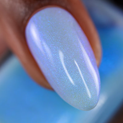 The Fire's Burning Blue by Cadillacquer, soft icy periwinkle base with dense blue-to-lavender iridescent shimmer in daylight, on a medium skin tone hand