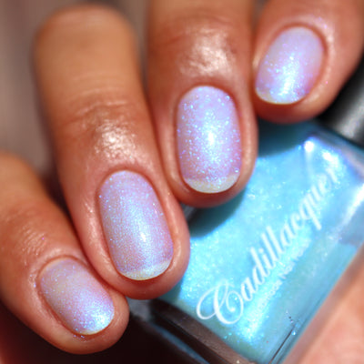The Fire's Burning Blue by Cadillacquer, soft blue shimmer shifting pink-violet in direct daylight, on a light-medium skin tone hand