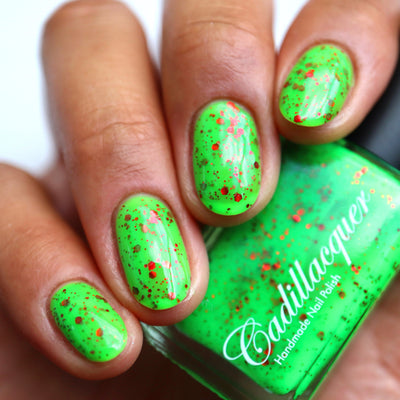 Light the Flame by Cadillacquer, electric green jelly with red metallic hex glitter and copper-brown micro particles, on a medium skin tone hand