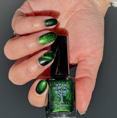 New Divide by Danglefoot Nail Polish, green shimmer jelly magnetic bottle held in a light hand