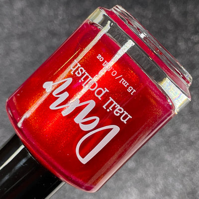 Cup of Cheer by Dam Nail Polish, rich red shimmer with red-to-orange ember glow, bottle standalone product shot