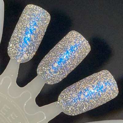 We're Off to See the Blizzard by Dam Nail Polish, dense silver reflective glitter with vivid blue shifting shimmer and scattered white holographic particles under direct flash, swatch stick