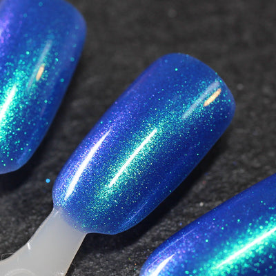 Cheers to 10 Years by Dam Nail Polish, cobalt blue shimmer with teal-green to purple color-shifting microflakes, swatch stick