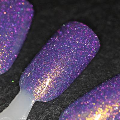 Decade of Dam by Dam Nail Polish, blue-violet base with purple reflective glitter flash and gold-to-green-to-blue shifting shimmer, swatch stick