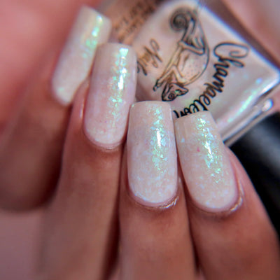 Purple Moon (UV Polish) by Chamaeleon Nails, creamy white resting state jelly with large green-turquoise multichrome flakies, on a light skin tone hand