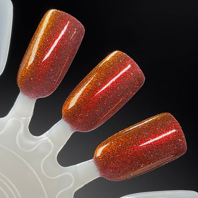 I'm Not Smart Enough by Dam Nail Polish, deep red base showing red-to-orange shifting shimmer with holographic microglitter under studio light, swatch stick