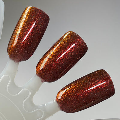 I'm Not Smart Enough by Dam Nail Polish, deep crimson base with fiery orange-red micro-glitter flaring under direct studio lighting, swatch stick