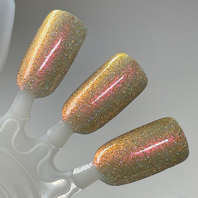 I Love Oklahoma by Dam Nail Polish, gold-green base showing amber-orange and rosy-red shimmer shifts with reflective gold glitter, swatch stick
