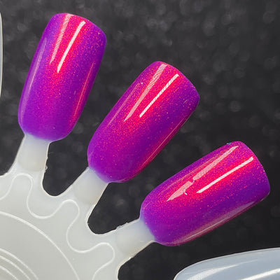 Dark Eyes Blossom by Dam Nail Polish, deep violet-purple base with vivid red-orange shimmer flash and fuchsia mid-tone blend, swatch stick