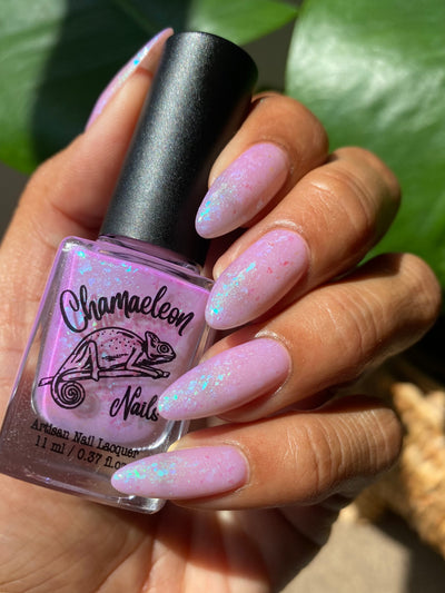 Purple Moon (UV Polish) by Chamaeleon Nails, milky lilac-pink UV-activated jelly loaded with green-teal-blue colour-shifting flakies, bottle held in a medium hand