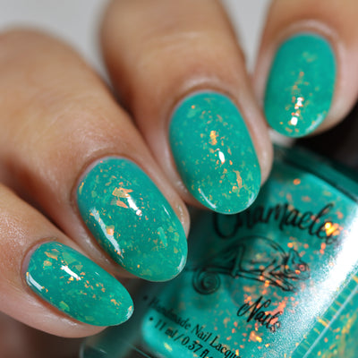 Kuang Si Falls by Chamaeleon Nails, neon teal flakie jelly showing copper-to-gold orange-to-yellow shifting flakes, on a light-medium skin tone hand