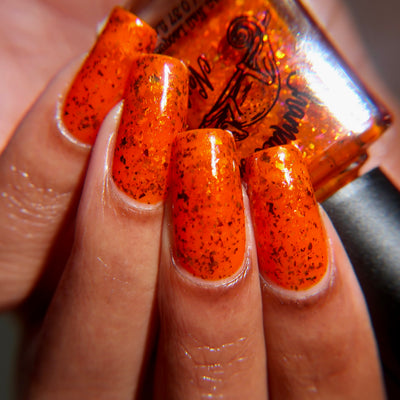 Sauron's Eye by Chamaeleon Nails, vivid orange-red jelly with gold-copper iridescent and copper-to-green UCC flakie highlights in bright daylight, on a light-medium skin tone hand