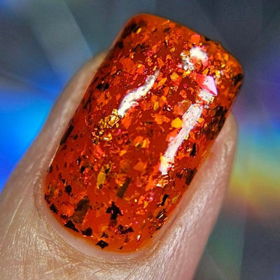 Sauron's Eye by Chamaeleon Nails, macro close-up of chunky copper-to-pink ultrachrome flakies with scattered iridescent shimmer pieces in deep fiery orange jelly base