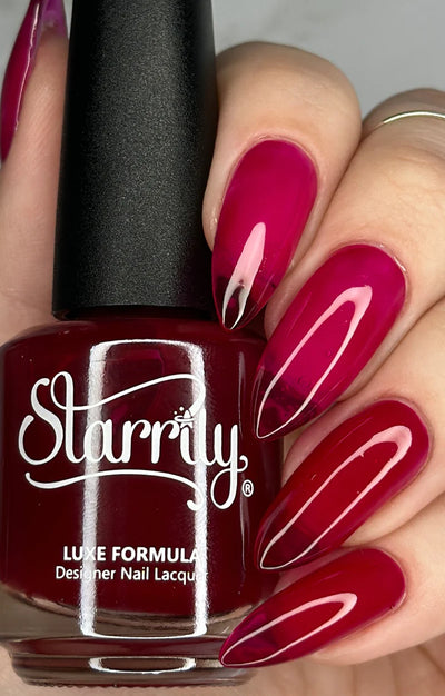 Bloodbelly Jelly by Starrily, burgundy-to-crimson red jelly with glass-like translucency and high-gloss shine, bottle held in a light hand
