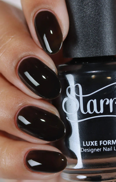 Immortal Jelly by Starrily, deep near-black brown-black jelly with high-gloss finish and subtle translucency, bottle held in a light skin tone hand