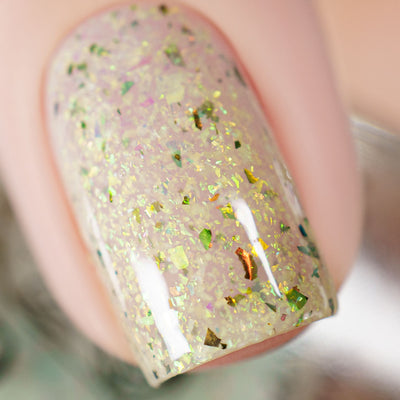 The Forgotten Lagoon (UV Polish) by Chamaeleon Nails, macro close-up of sheer milky white jelly base in resting state with green-gold iridescent flakes and copper-bronze UCC shards
