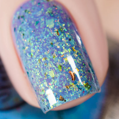The Forgotten Lagoon (UV Polish) by Chamaeleon Nails, macro close-up of periwinkle blue UV-activated jelly base with large green-to-copper iridescent flakes and bronze ultrachrome shards