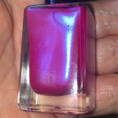 80s Hair by Prairie Crocus Polish, magenta-pink base with blue-violet duochrome shimmer under direct flash, bottle held in a medium skin tone hand