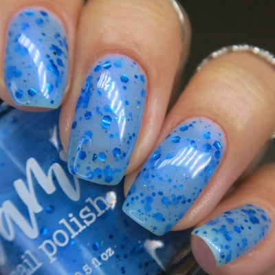 Blueberry Sanctuary by Dam Nail Polish, sheer misty light blue crelly with metallic blue hex and dot glitters, blue-to-purple shifting shimmer, and holographic microglitter, on a light skin tone hand