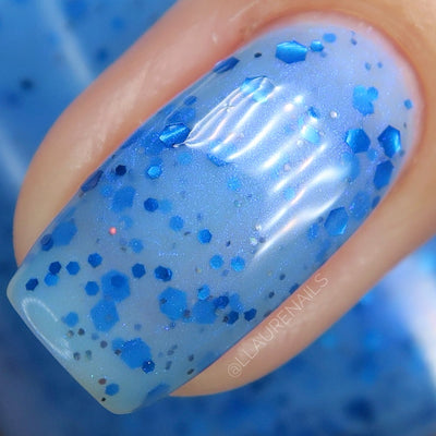Blueberry Sanctuary by Dam Nail Polish, macro close-up of sheer blue crelly base with mixed-size royal blue hex and irregular metallic glitters and blue-violet shifting shimmer