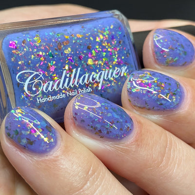 Cadillacquer Don't Worry purple pink chameleon iridescent crelly nail polish, bottle held with four-nail swatch, light skin, studio lighting