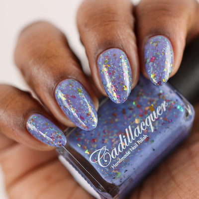 Cadillacquer Don't Worry purple pink chameleon iridescent crelly nail polish, bottle held with four-nail swatch, deep skin, studio lighting
