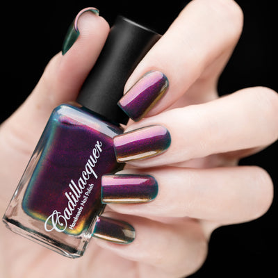 Multichrome shimmer Cadillacquer nail polish in Fear What You Will Become, shown in bottle held in hand with five swatched squoval nails, shifting from deep burgundy-plum through magenta and amber-bronze to dark teal at edges, light skin tone, studio lighting, swatched by @rafinails