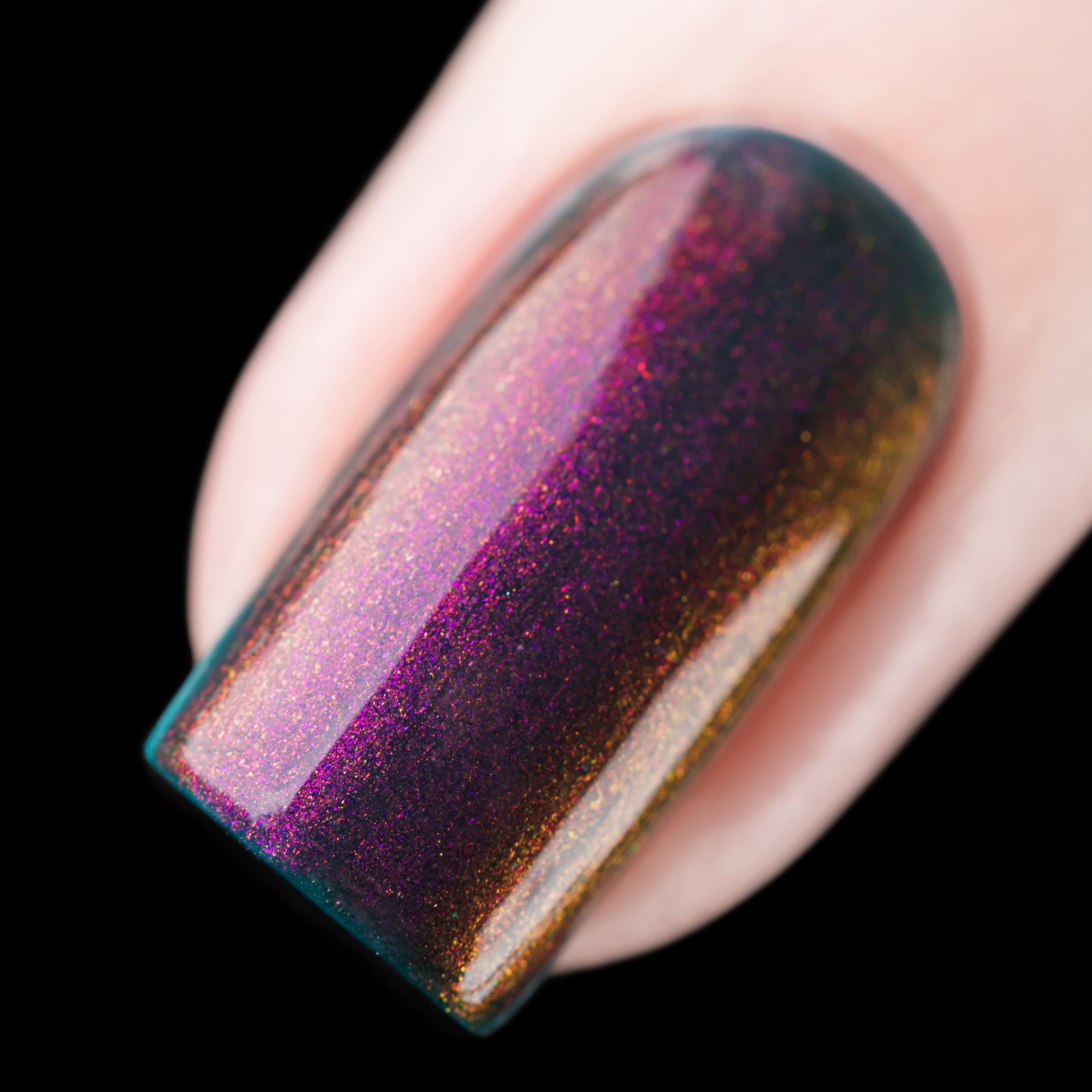 Multichrome holographic shimmer Cadillacquer nail polish in Fear What You Will Become, shown as a macro swatch on one square nail, the polish shifts from a deep blackened teal at the side wall through dark burgundy-plum at the face to vivid magenta, amber-gold, and violet-purple at angular shimmer flashes, densely packed with fine holographic micro-flakes, light skin tone, studio lighting against a black background, swatched by @rafinails