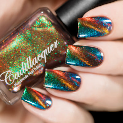 Holographic magnetic multichrome Cadillacquer nail polish in Once You See It, shown in bottle held against four swatched nails displaying vivid green-to-blue aurora shimmer with an orange magnetic band stripe across a deep teal field, light skin tone, studio lighting, swatched by @rafinails