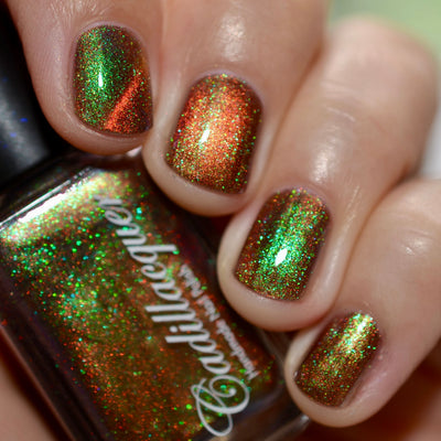 Holographic magnetic multichrome Cadillacquer nail polish in Once You See It, shown on five short natural nails and held bottle, with a deep red-brown carrier base, vivid copper-orange magnetic band, and intense green-to-teal aurora shimmer flash packed with fine holographic particles, on light-medium skin tone, in bright daylight, swatched by @caitlinswatches