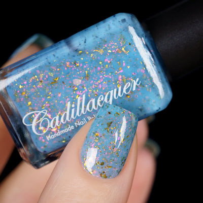 Cadillacquer Slow Mornings light blue gold chameleon iridescent crelly nail polish, bottle held with one-nail swatch, light skin, studio lighting