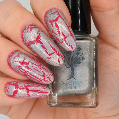 Castle of Glass (Crackle) by Danglefoot Nail Polish, silver holographic crackle topper bottle held in a light hand