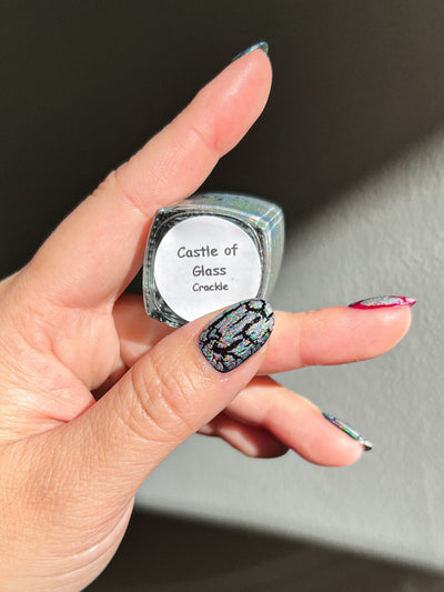 Castle of Glass (Crackle) by Danglefoot Nail Polish, silver holographic crackle topper bottle held in a light hand