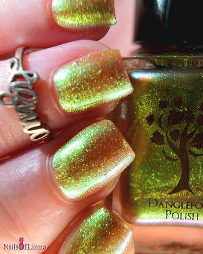 Flame On by Danglefoot Nail Polish, gold-green duochrome shimmer bottle held in a light-medium hand