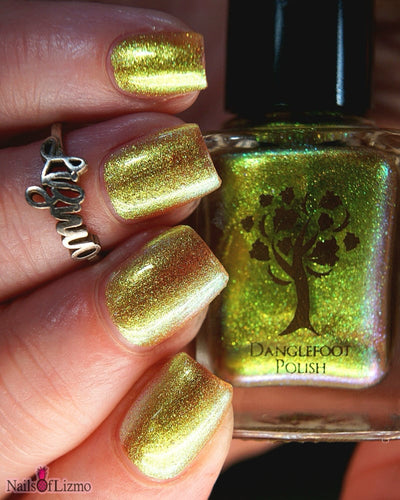 Flame On by Danglefoot Nail Polish, gold-green duochrome shimmer bottle held in a light-medium hand