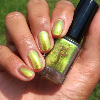 Flame On by Danglefoot Nail Polish, gold-green duochrome shimmer bottle held in a light-medium hand