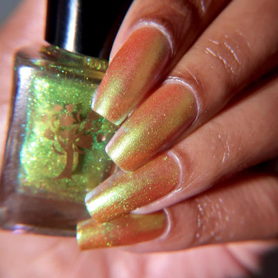 Flame On by Danglefoot Nail Polish, gold-green duochrome shimmer bottle held in a light-medium hand