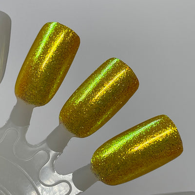 Monkey by Dam Nail Polish, golden yellow base showing warm amber undertones with vivid yellow-to-green duochrome shimmer shift, swatch stick