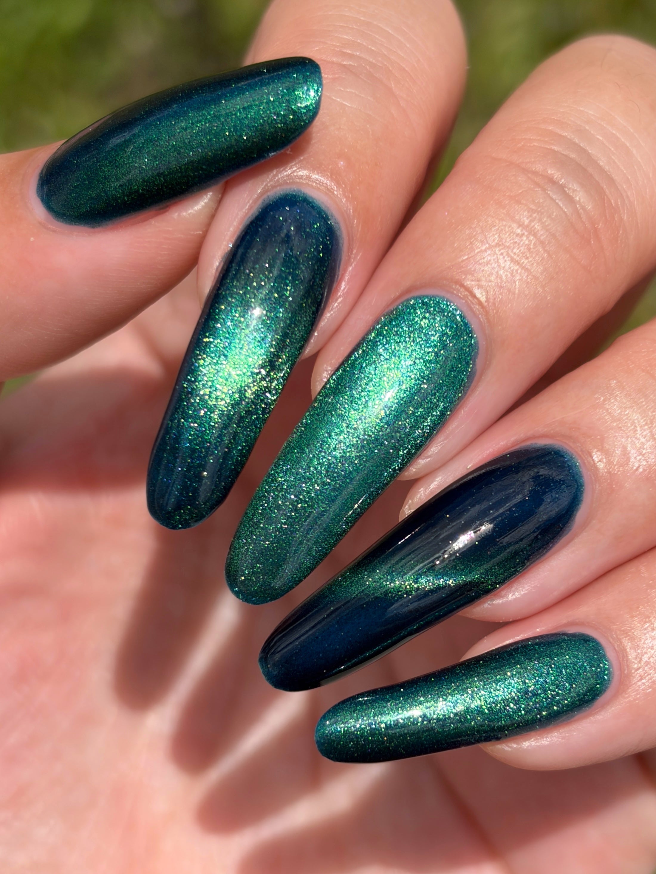 Do-Nuts by Glitch Lacquer, deep blue jelly, green-to-teal magnetic cat-eye, on light-medium skin tone almond nails