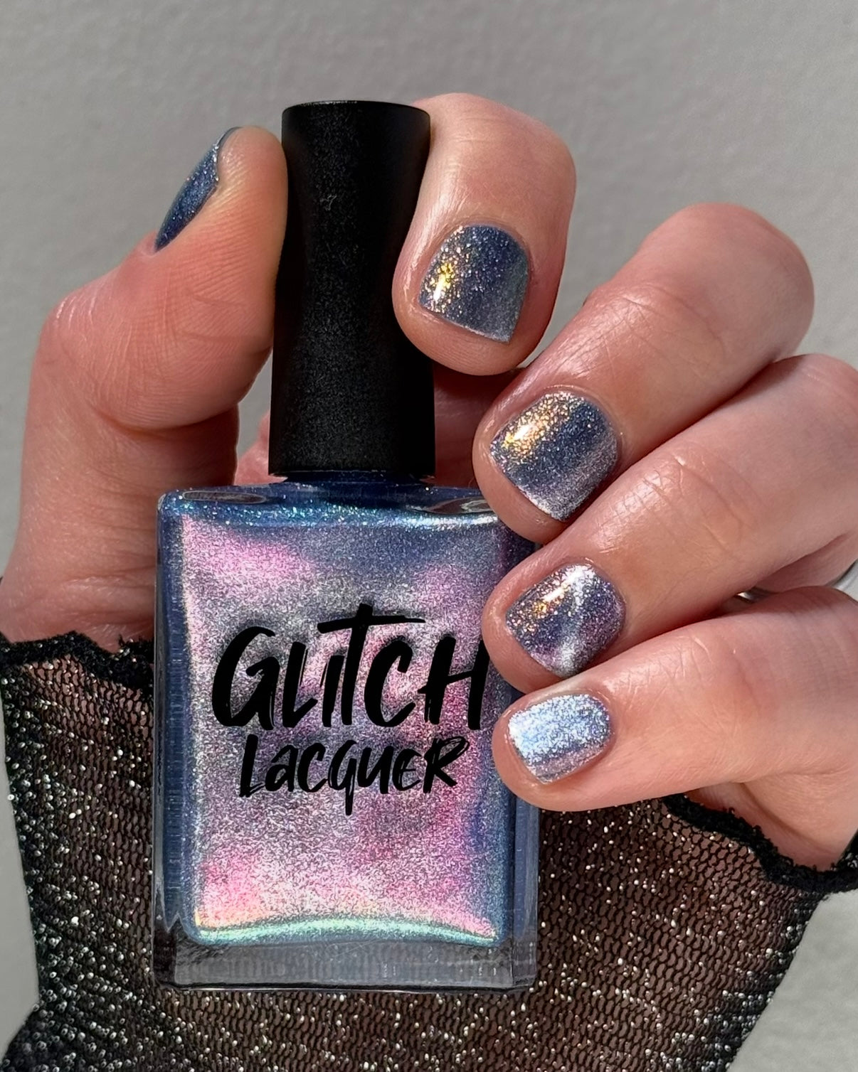 Protect the Dolls by Glitch Lacquer, blue jelly, color-shift shimmer, silver magnetic, bottle in hand on light skin tone