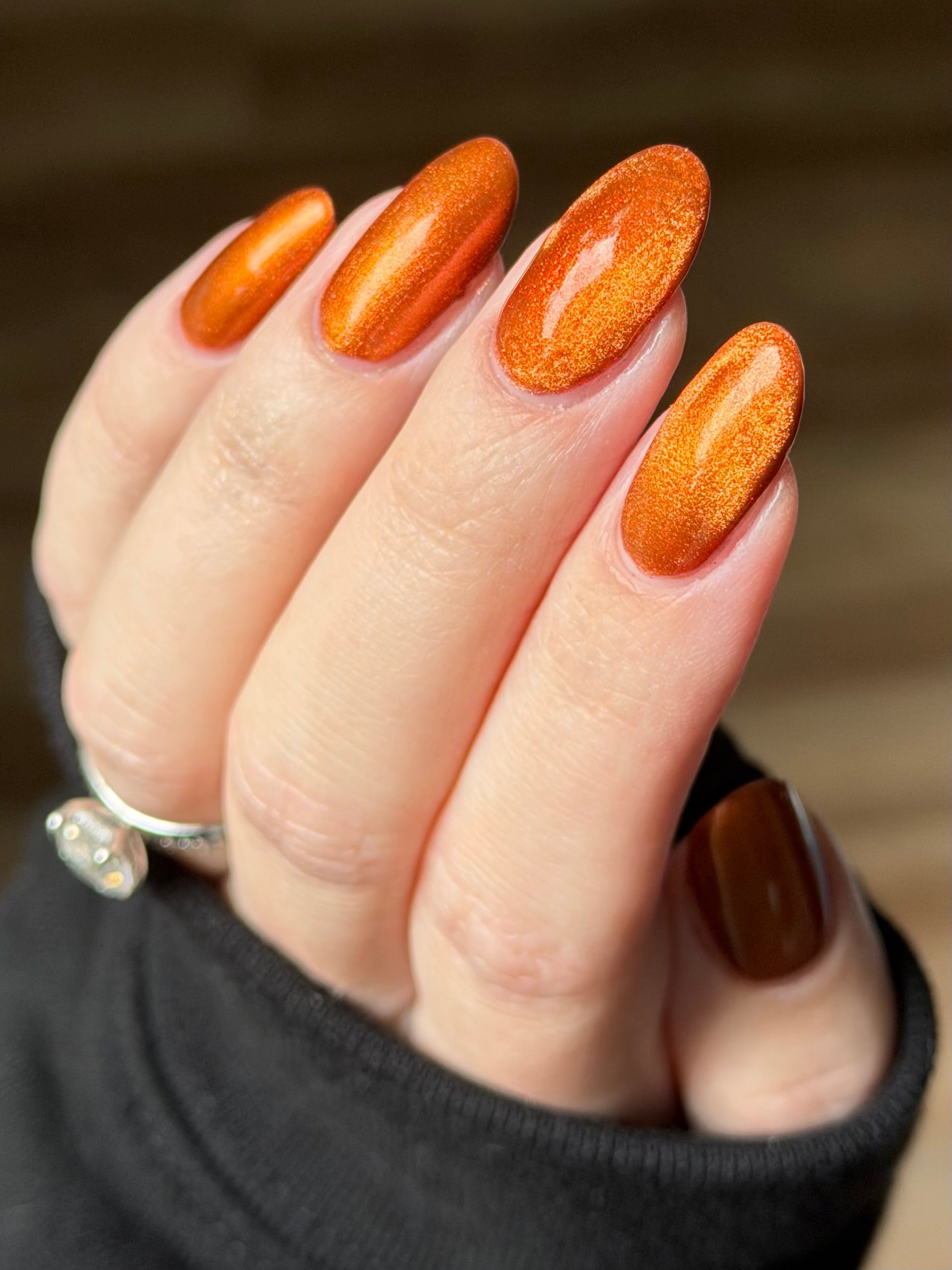 Marigold by Glitch Lacquer, burnt orange jelly, red shimmer, orange-to-gold magnetic, on light skin tone almond nails
